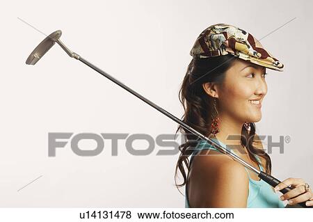 Side profile of a young woman holding a golf club and smiling View Large Photo Image Stock Photo - Side profile of a young woman holding a golf club and smiling. Fotosearch