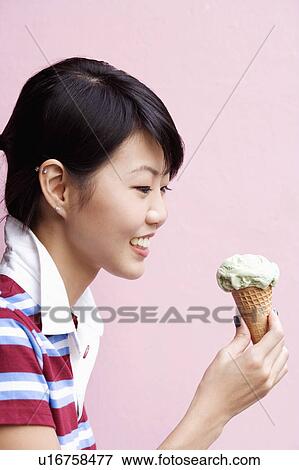 Side profile of a young woman holding an ice-cream cone View Large Photo Image Stock Photo - Side profile of a young woman holding an ice-cream cone. Fotosearch