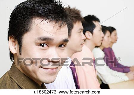 Stock Image - Three businessmen and two businesswomen sitting side by side. Fotosearch