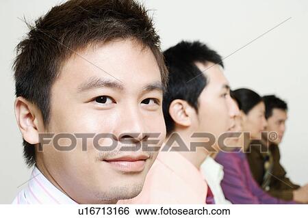 Stock Photograph - Three businessmen and two businesswomen sitting side by side. Fotosearch