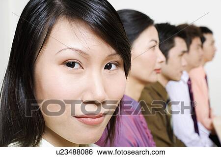 Stock Photograph - Three businessmen and two businesswomen sitting side by side. Fotosearch