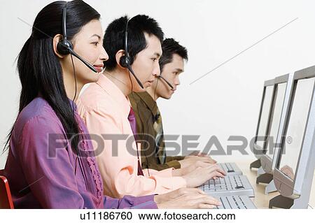 Stock Image - Three customer service representatives working on computers. Fotosearch