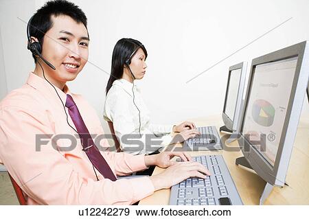 Stock Photo - Two customer service representatives working on a computer. Fotosearch
