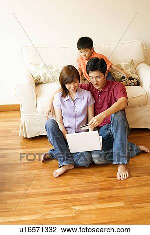 Stock Image - Young couple shopping online with a credit card and their son beside them. Fotosearch