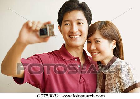 Stock Image - Young couple taking a picture of themselves. Fotosearch