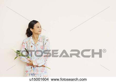 Young woman holding a flower View Large Photo Image Picture - Young woman holding a flower. Fotosearch