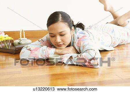 Young woman lying in front of a tea cup View Large Photo Image Stock Image - Young woman lying in front of a tea cup. Fotosearch