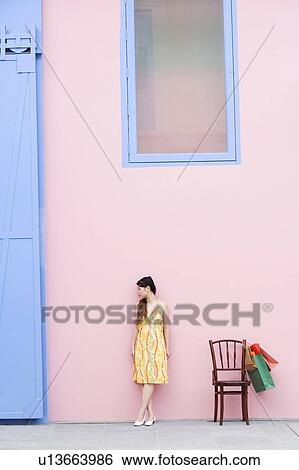 Stock Photograph - Young woman standing beside a chair. Fotosearch