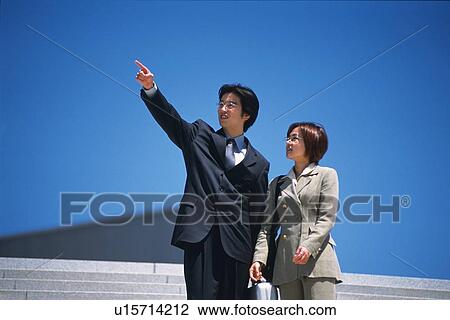 Businessman and businesswoman looking and pointing at something, Low Angle View View Large Photo Image Stock Image - Businessman and businesswoman looking and pointing at something, Low Angle View. Fotosearch