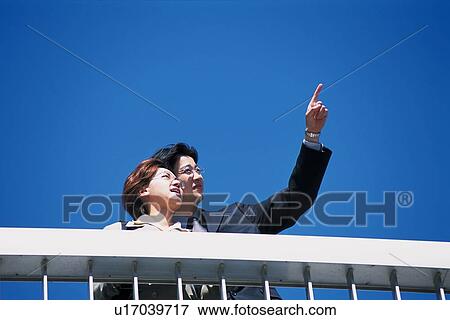 Businessman and businesswoman looking and pointing at something, Low Angle View View Large Photo Image Stock Photo - Businessman and businesswoman looking and pointing at something, Low Angle View. Fotosearch