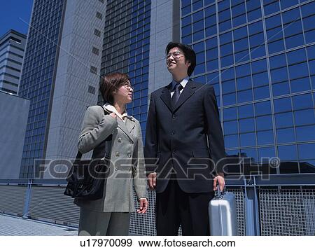 Stock Photo - Businessman and businesswoman looking at something by the high rise building, Low Angle View. Fotosearch