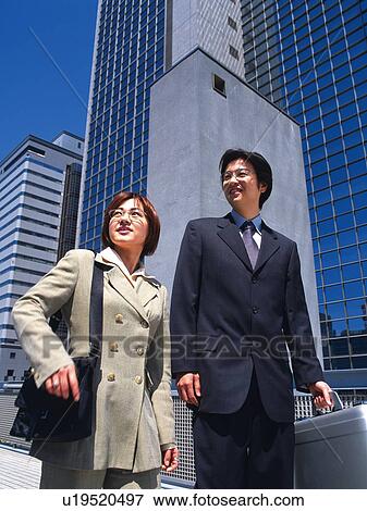 Stock Photo - Businessman and businesswoman looking at something by the high rise building, Low Angle View. Fotosearch