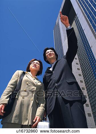 Businessman and businesswoman pointing and looking at something by the high rise building, Low Angle View View Large Photo Image Stock Image - Businessman and businesswoman pointing and looking at something by the high rise building, Low Angle View. Fotosearch
