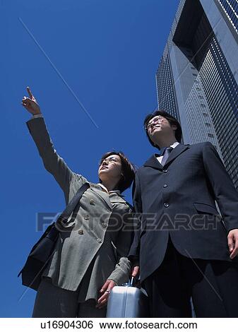 Businessman and businesswoman pointing and looking at something by the high rise building, Low Angle View View Large Photo Image Stock Photograph - Businessman and businesswoman pointing and looking at something by the high rise building, Low Angle View. Fotosearch