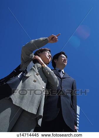 Businessman and businesswoman pointing and looking at something, Low Angle View View Large Photo Image Stock Photography - Businessman and businesswoman pointing and looking at something, Low Angle View. Fotosearch
