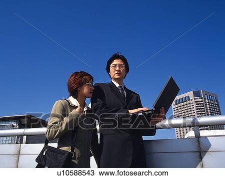 Businessman and businesswoman standing with laptop computer, Low Angle View View Large Photo Image Stock Image - Businessman and businesswoman standing with laptop computer, Low Angle View. Fotosearch