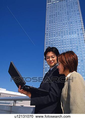Businessman and businesswoman standing near high rise building with laptop computer, Low Angle View View Large Photo Image Stock Image - Businessman and businesswoman standing near high rise building with laptop computer, Low Angle View. Fotosearch
