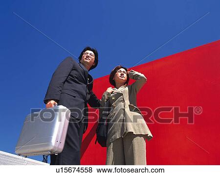 Businessman and businesswoman standing by the red Wall, Low Angle View View Large Photo Image Stock Photo - Businessman and businesswoman standing by the red Wall, Low Angle View. Fotosearch