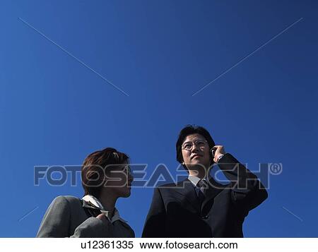 Businessman and businesswoman standing under the sky, Low Angle View View Large Photo Image Stock Photography - Businessman and businesswoman standing under the sky, Low Angle View. Fotosearch