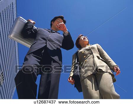 Stock Photo - Businessman and businesswoman walking, Low Angle View. Fotosearch
