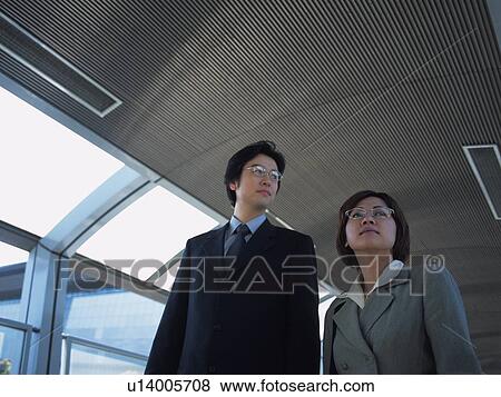 Businessman and businesswoman walking together, Low Angle View View Large Photo Image Stock Photo - Businessman and businesswoman walking together, Low Angle View. Fotosearch