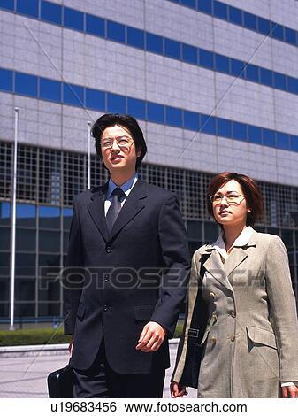 Businessman and businesswoman walking by the side of building, Front View View Large Photo Image Stock Photograph - Businessman and businesswoman walking by the side of building, Front View. Fotosearch