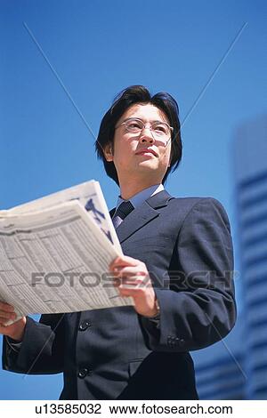 Stock Image - Businessman holding news paper, Low Angle View. Fotosearch