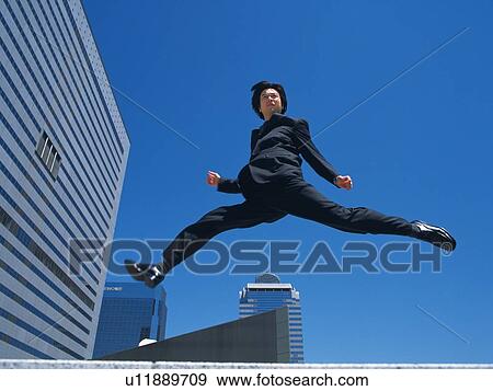 Stock Photo - Businessman jumping, Low Angle View. Fotosearch