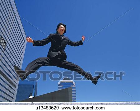 Stock Photo - Businessman jumping, Low Angle View. Fotosearch