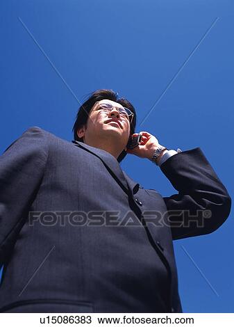 Businessman looking away and holding mobile phone, Low Angle View View Large Photo Image Stock Image - Businessman looking away and holding mobile phone, Low Angle View. Fotosearch