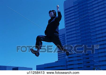 Stock Image - Businessman running and jumping, Low Angle View. Fotosearch