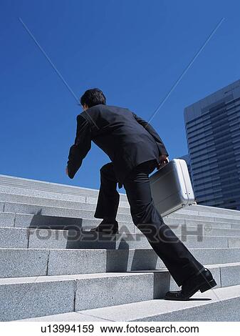 Stock Photo - Businessman running up the stairs, Low Angle View. Fotosearch