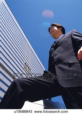 Businessman standing by the side of building, Low Angle View View Large Photo Image Stock Image - Businessman standing by the side of building, Low Angle View. Fotosearch