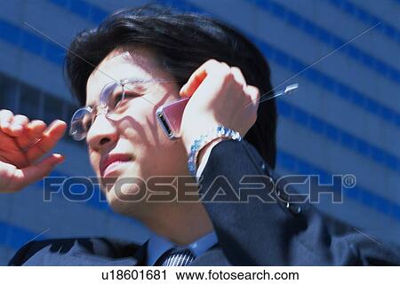 Stock Image - Businessman using mobile phone, Low Angle View. Fotosearch