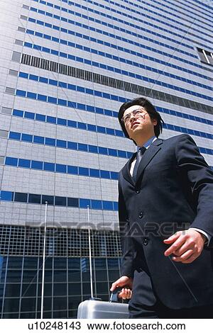 Businessman walking by the side of building, Low Angle View View Large Photo Image Stock Image - Businessman walking by the side of building, Low Angle View. Fotosearch