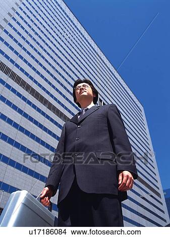 Businessman with business case standing by the side of building, Low Angle View View Large Photo Image Picture - Businessman with business case standing by the side of building, Low Angle View. Fotosearch