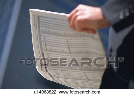 Stock Image - Hand holding news paper, Side View. Fotosearch
