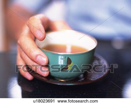 Stock Image - Hand of the senior adult man holding a cup of tea, Close Up. Fotosearch