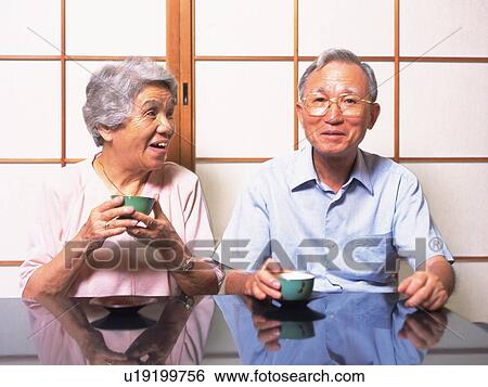 Stock Photograph - Senior adult man and woman having a tea break, Front View. Fotosearch