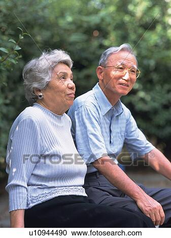 Stock Image - Senior adult man and woman sitting together, Side View. Fotosearch
