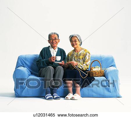 Stock Photography - Senior adult man and woman sitting together on a sofa, Front View. Fotosearch