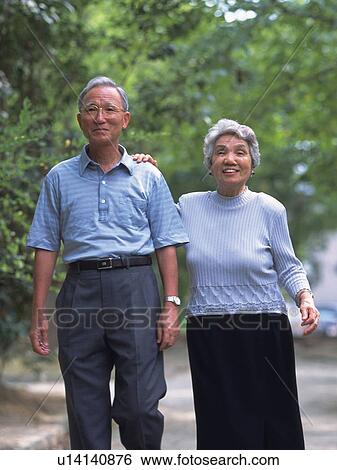 Stock Photograph - Senior adult man and woman walking together, Front View. Fotosearch