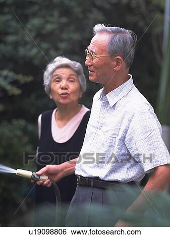 Senior adult man and woman watering the garden, Side View View Large Photo Image Stock Photograph - Senior adult man and woman watering the garden, Side View. Fotosearch