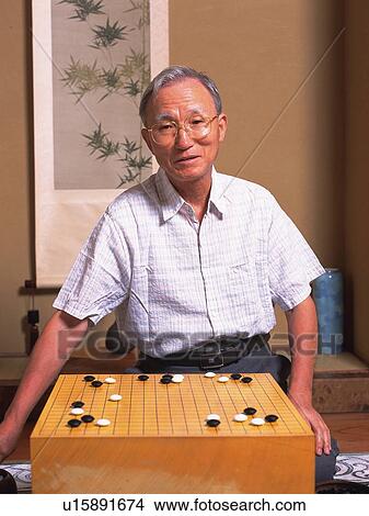 Picture - Senior adult man playing Go, Front View. Fotosearch
