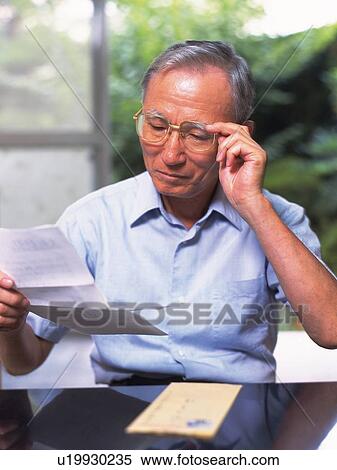 Stock Photography - Senior adult man reading a letter, High Angle View. Fotosearch