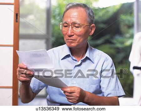 Stock Photo - Senior adult man reading a letter, Front View. Fotosearch