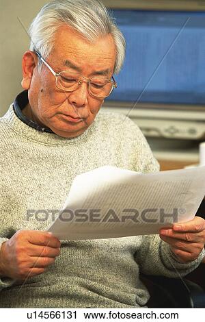 Stock Image - Senior adult man reading documents, Front View. Fotosearch