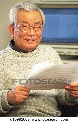 Stock Photo - Senior adult man smiling at camera with documents in hands, Front View. Fotosearch