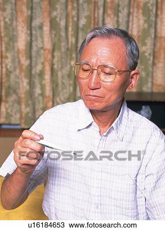 Stock Image - Senior adult man taking temperature, Front View. Fotosearch
