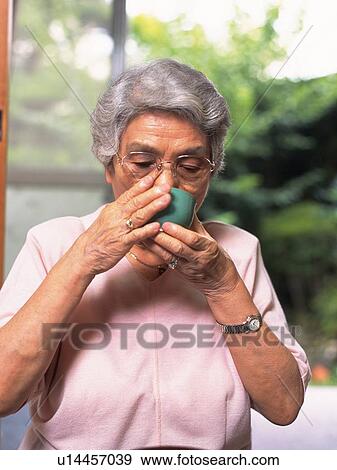 Stock Photo - Senior adult woman drinking a cup of tea, Front View. Fotosearch